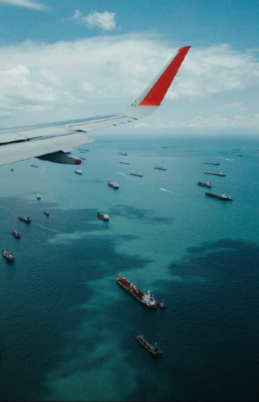 plane flying over cargo ships